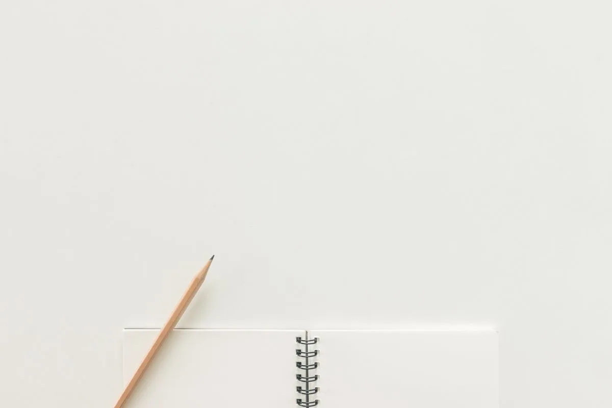 Minimal notebook and pencil on a white desk
